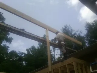 Carpenter setting a ridge beam over a new addition frame — Ice Dam Removal by Roofing Brothers in Quogue