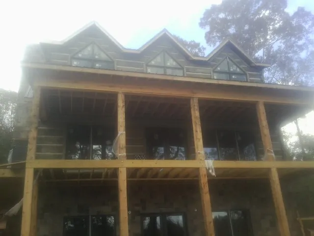 Dormers and porch framing on a large log home under construction — Roof Coating work by our crew in Quogue
