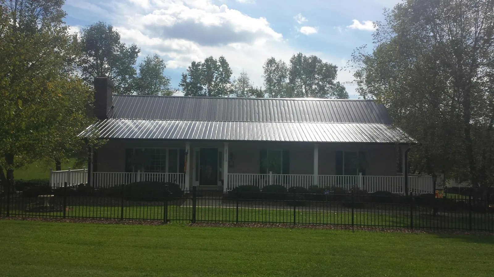 Gray metal roof on a brick ranch with a full width front porch — Gutter Guard Installation work by our crew in Quogue