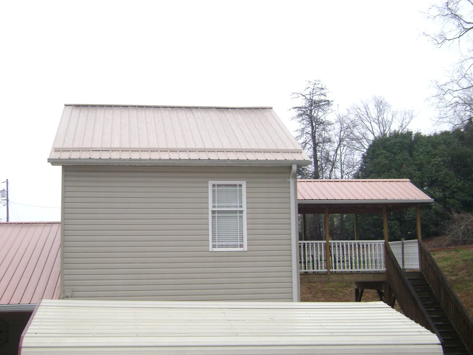 Tan metal roofs on a two story addition and attached porch, from a Roof Replacement job in Quogue