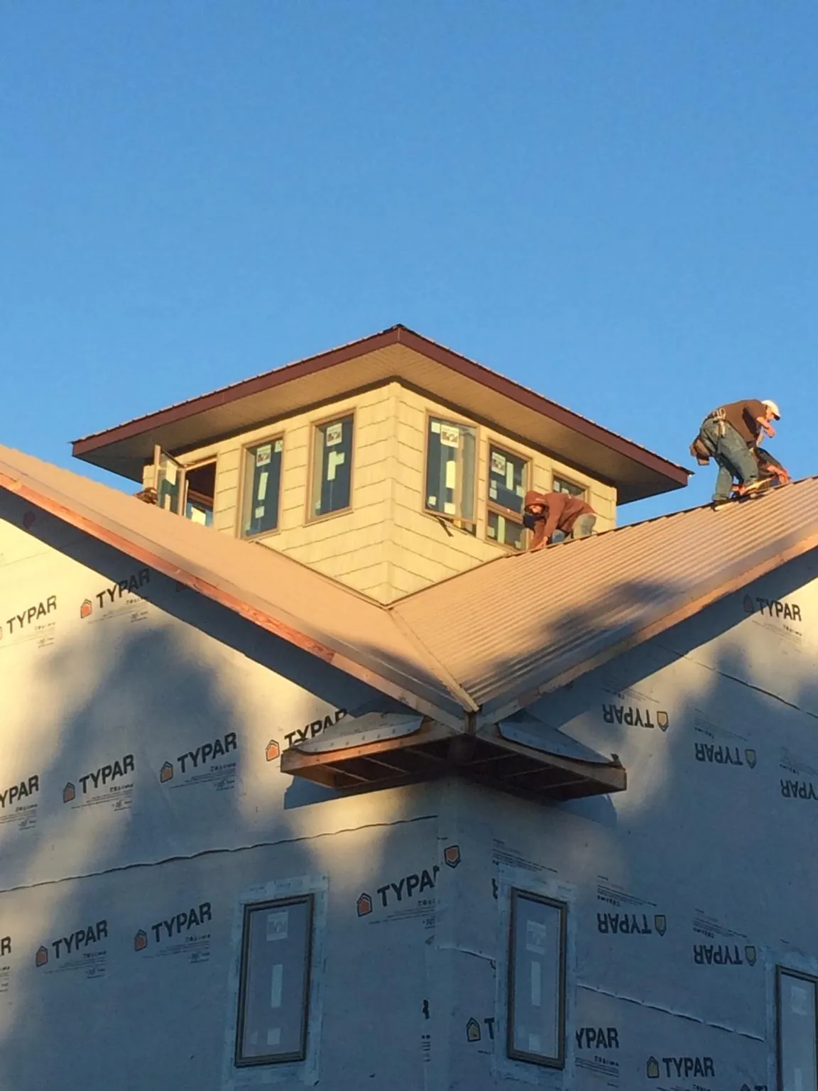 Roofers working around a rooftop cupola on a new metal roof at sunset — Roof Waterproofing in Quogue by Roofing Brothers